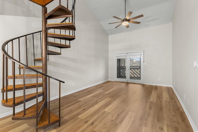 stairs with ceiling fan, wood-type flooring, and high vaulted ceiling