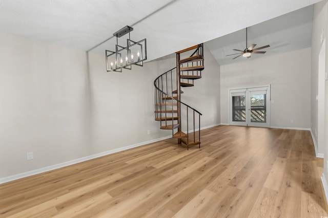 unfurnished living room with vaulted ceiling, ceiling fan with notable chandelier, and light wood-type flooring