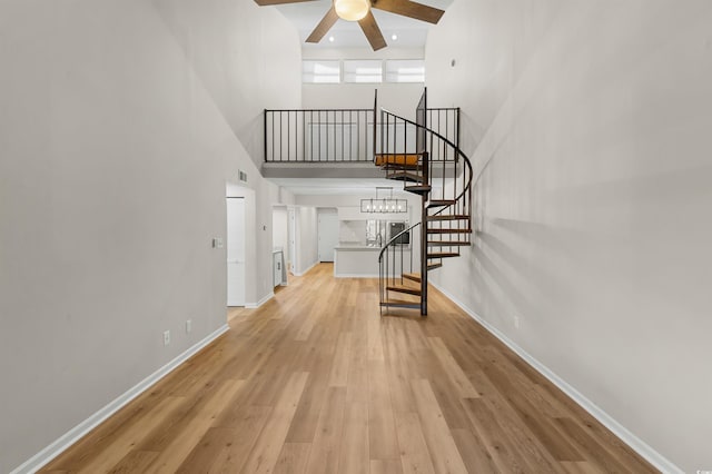 interior space featuring ceiling fan, hardwood / wood-style floors, and a high ceiling