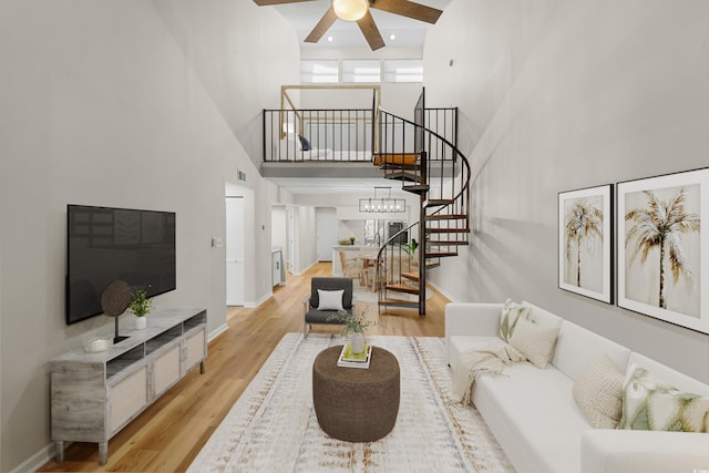 living room with a high ceiling, light hardwood / wood-style flooring, and ceiling fan