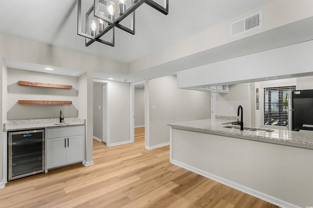 kitchen with light stone countertops, sink, and beverage cooler