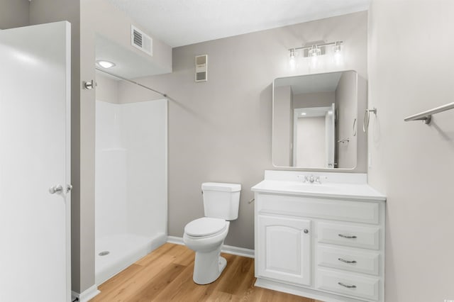 bathroom featuring toilet, hardwood / wood-style floors, vanity, and walk in shower