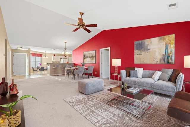 carpeted living room with ceiling fan with notable chandelier and vaulted ceiling