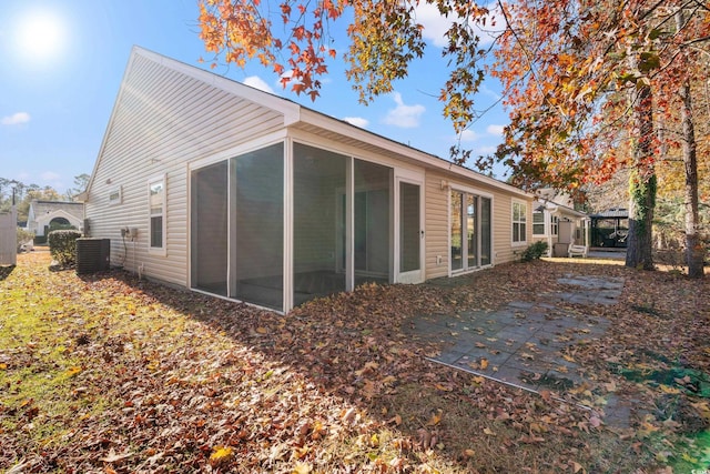 rear view of property featuring a sunroom and central AC unit