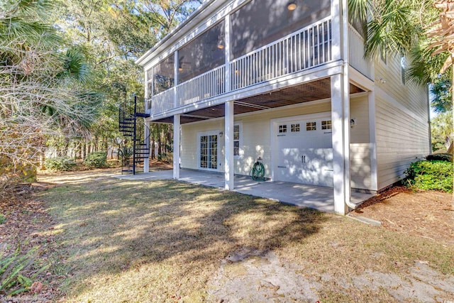 back of house featuring a lawn, a sunroom, a patio, and a garage