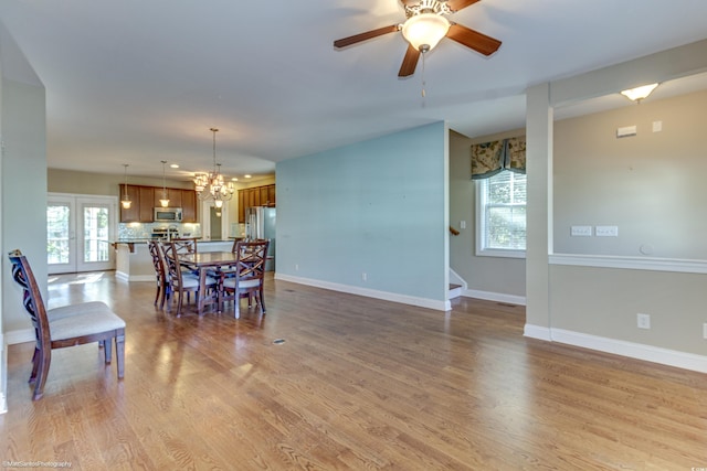 dining area featuring french doors, ceiling fan with notable chandelier, light hardwood / wood-style flooring, and a healthy amount of sunlight