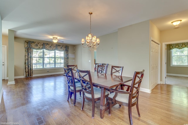 dining space with ceiling fan with notable chandelier, a healthy amount of sunlight, and light wood-type flooring