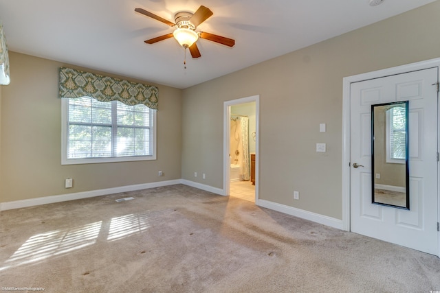 unfurnished bedroom with light carpet, ensuite bath, and ceiling fan