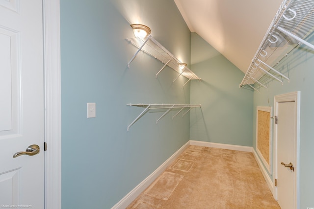 spacious closet featuring light colored carpet and lofted ceiling