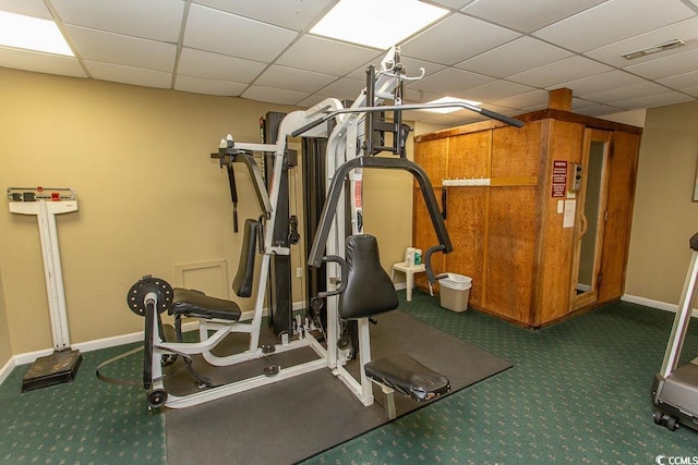 workout room with a paneled ceiling and dark carpet