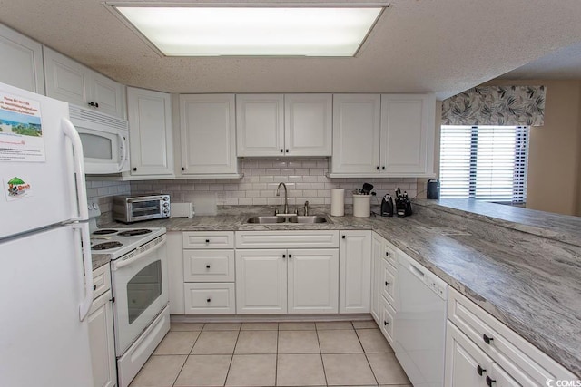 kitchen featuring tasteful backsplash, white cabinetry, sink, and white appliances