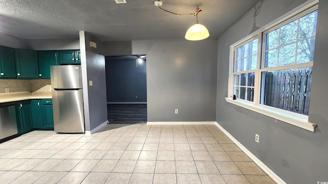 kitchen with stainless steel appliances, light countertops, hanging light fixtures, light tile patterned flooring, and baseboards