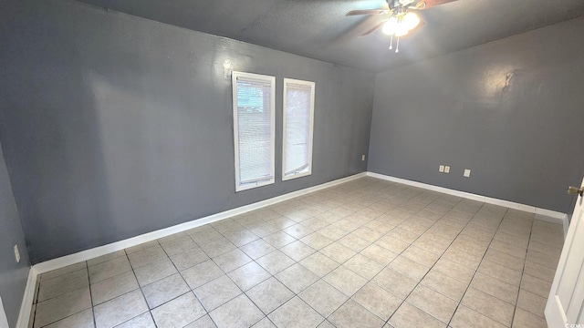 spare room featuring ceiling fan, light tile patterned floors, and baseboards