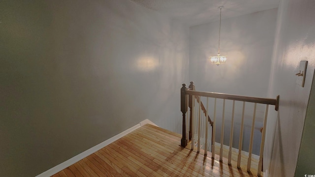 stairway with an inviting chandelier, baseboards, and wood finished floors