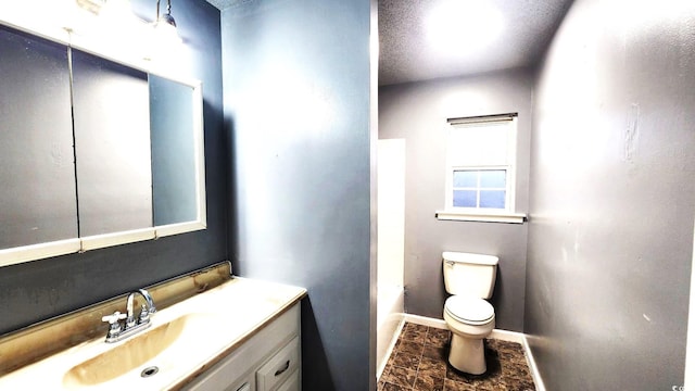 bathroom featuring baseboards, vanity, and toilet