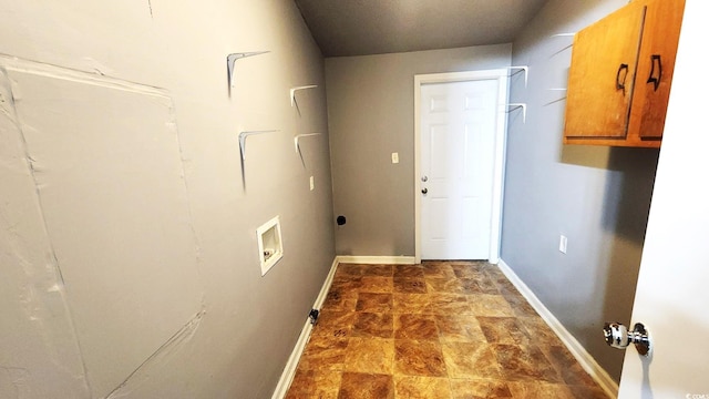 laundry room featuring stone finish flooring, washer hookup, cabinet space, and baseboards