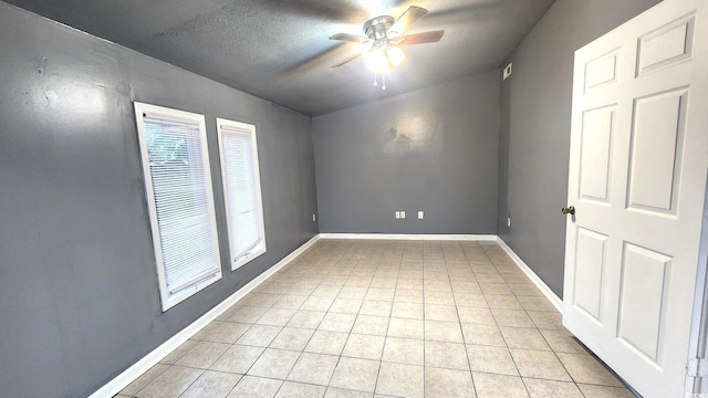 empty room with a ceiling fan, a textured ceiling, baseboards, and light tile patterned floors