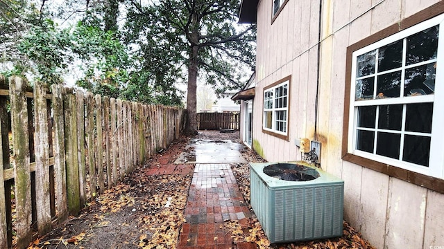 view of side of home featuring a patio, a fenced backyard, and central air condition unit