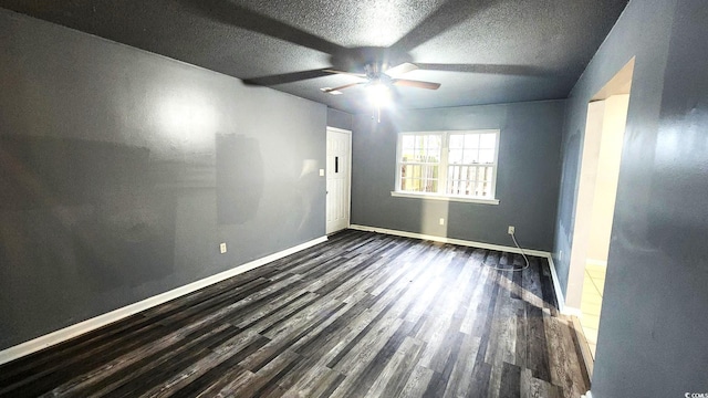 spare room with a ceiling fan, a textured ceiling, baseboards, and dark wood-style flooring