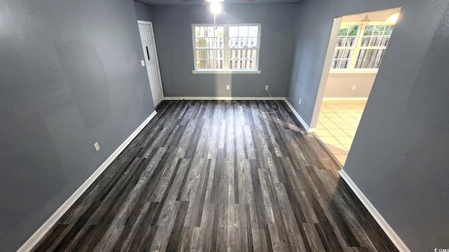 empty room with dark wood-style flooring, ceiling fan, and baseboards