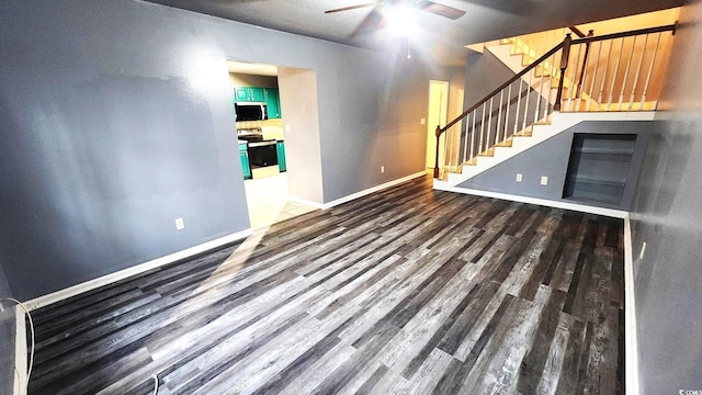 unfurnished living room with baseboards, stairway, dark wood finished floors, and a ceiling fan