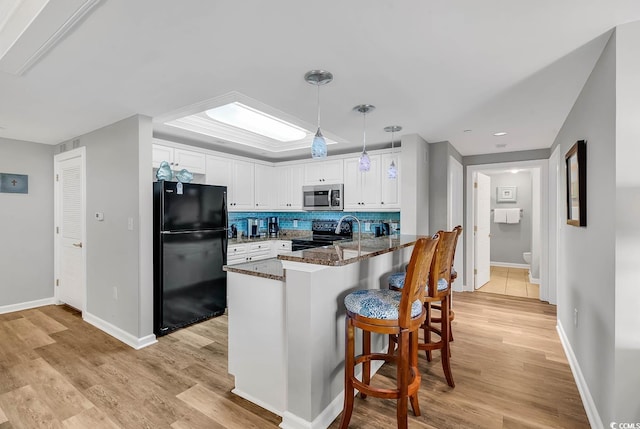 kitchen featuring white cabinetry, kitchen peninsula, pendant lighting, light hardwood / wood-style floors, and black appliances