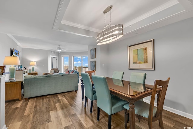 dining space with ceiling fan with notable chandelier, hardwood / wood-style flooring, crown molding, and a tray ceiling