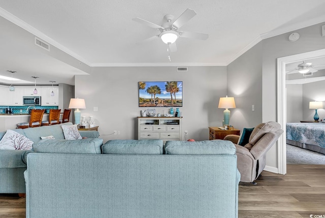 living room featuring ceiling fan, light hardwood / wood-style flooring, and ornamental molding