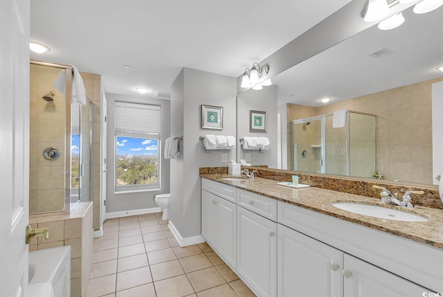 bathroom featuring tile patterned flooring, vanity, toilet, and a shower with shower door