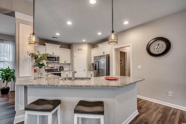 kitchen with dark wood-type flooring, white cabinets, sink, light stone countertops, and appliances with stainless steel finishes