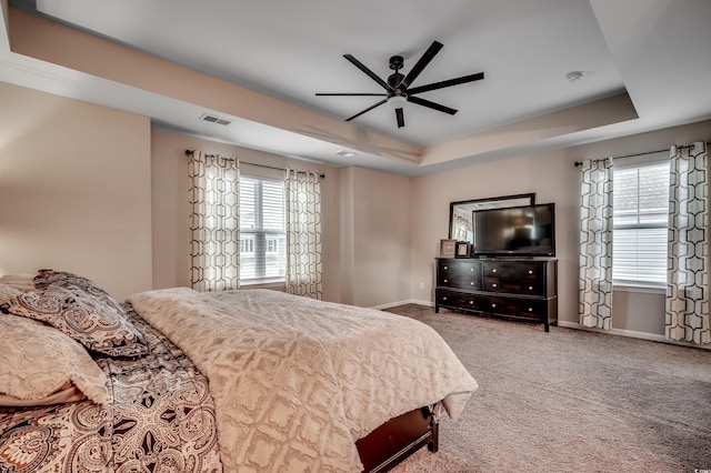 carpeted bedroom with ceiling fan and a tray ceiling