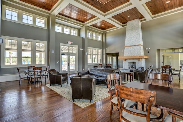 living room featuring a stone fireplace, a high ceiling, wooden ceiling, and dark hardwood / wood-style floors