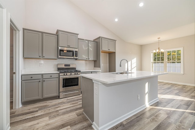 kitchen featuring gray cabinetry, sink, stainless steel appliances, light hardwood / wood-style flooring, and a notable chandelier