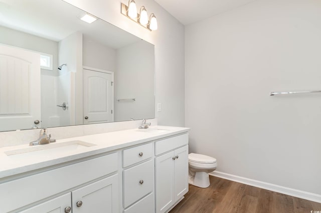 bathroom with hardwood / wood-style floors, vanity, toilet, and walk in shower