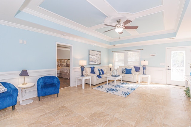 living room with ceiling fan, a raised ceiling, and ornamental molding