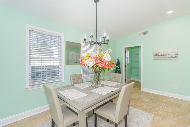 dining area with lofted ceiling, light tile patterned floors, and an inviting chandelier