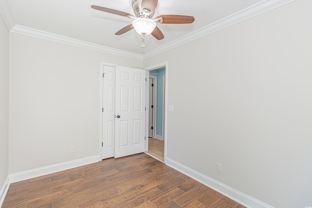 empty room with ceiling fan, dark hardwood / wood-style flooring, and crown molding