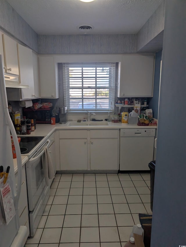 kitchen with white cabinets, light tile patterned floors, white appliances, and sink