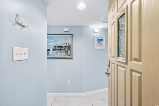 corridor with light tile patterned flooring and a textured ceiling