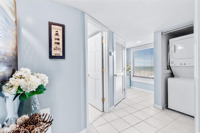 corridor featuring light tile patterned floors, a textured ceiling, and stacked washer / dryer