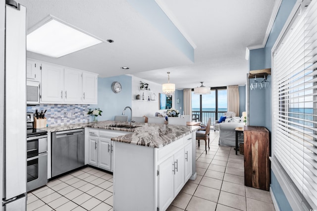 kitchen with sink, backsplash, kitchen peninsula, white cabinets, and appliances with stainless steel finishes