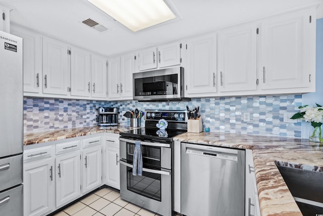 kitchen with light tile patterned flooring, white cabinetry, stainless steel appliances, and tasteful backsplash