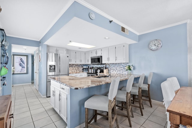 kitchen featuring white cabinets, light stone countertops, ornamental molding, and appliances with stainless steel finishes