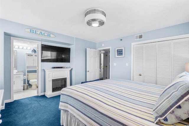 bedroom with ensuite bath, a closet, and dark colored carpet