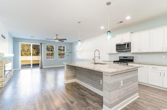 kitchen featuring stainless steel appliances, sink, a center island with sink, and white cabinets