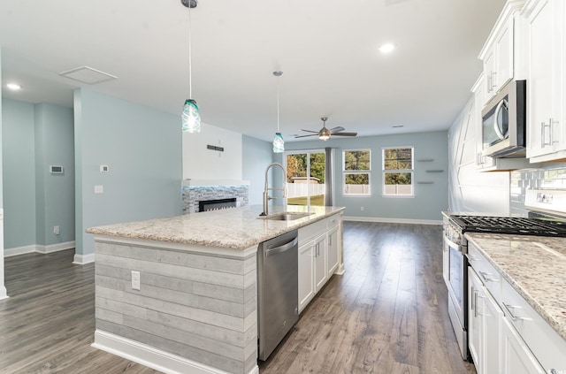 kitchen featuring appliances with stainless steel finishes, pendant lighting, an island with sink, sink, and white cabinets