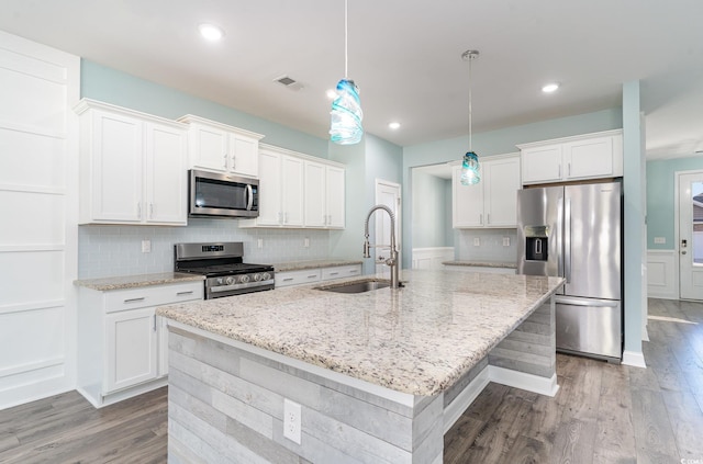 kitchen featuring sink, a kitchen island with sink, stainless steel appliances, white cabinets, and decorative light fixtures