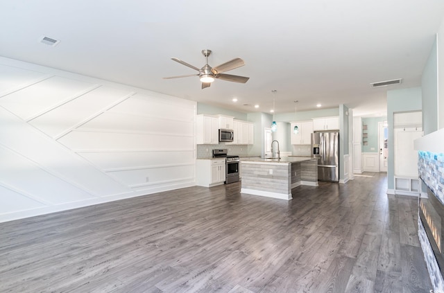 kitchen featuring pendant lighting, an island with sink, sink, white cabinets, and stainless steel appliances