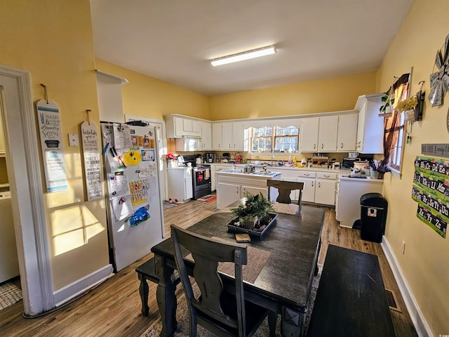 kitchen with white cabinetry, electric range, and hardwood / wood-style flooring