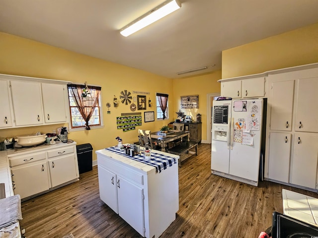 kitchen featuring white fridge with ice dispenser, dark wood-type flooring, and white cabinets